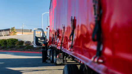 A man working on a red tractor trailer.